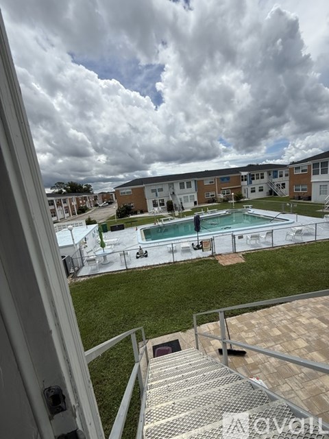 A view from a balcony looking out at a pool and apartment buildings.