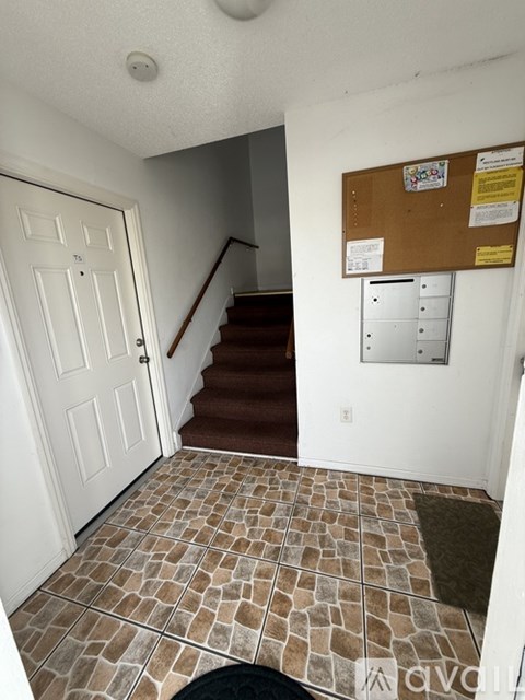 A hallway with a white door and a brown carpeted staircase.