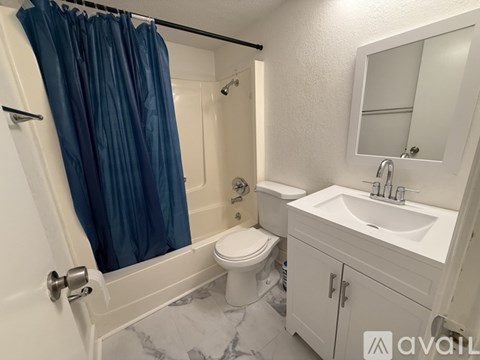A bathroom with a white toilet, a sink, and a blue shower curtain.