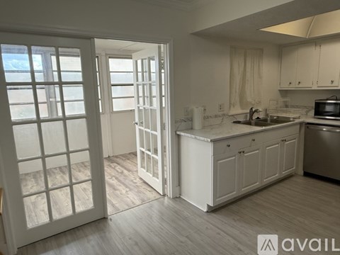 A kitchen with white cabinets and a wooden floor.