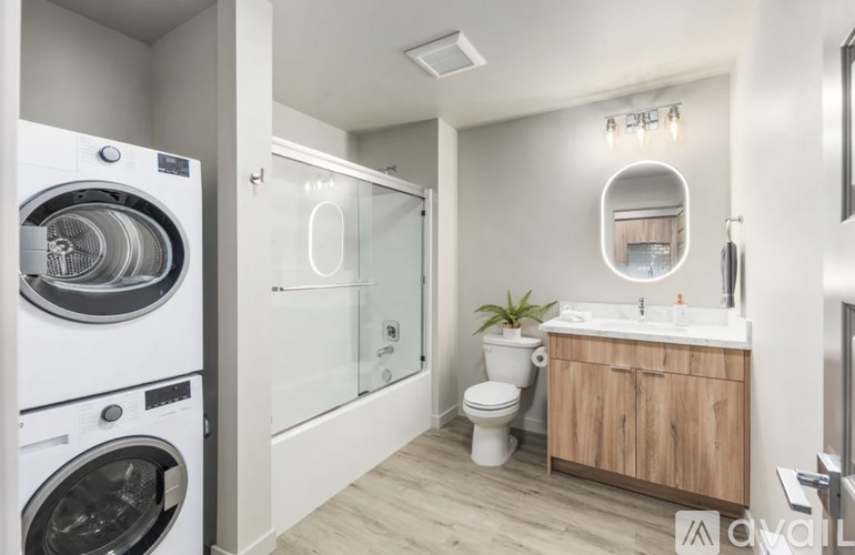 A modern bathroom with a washing machine next to the toilet.