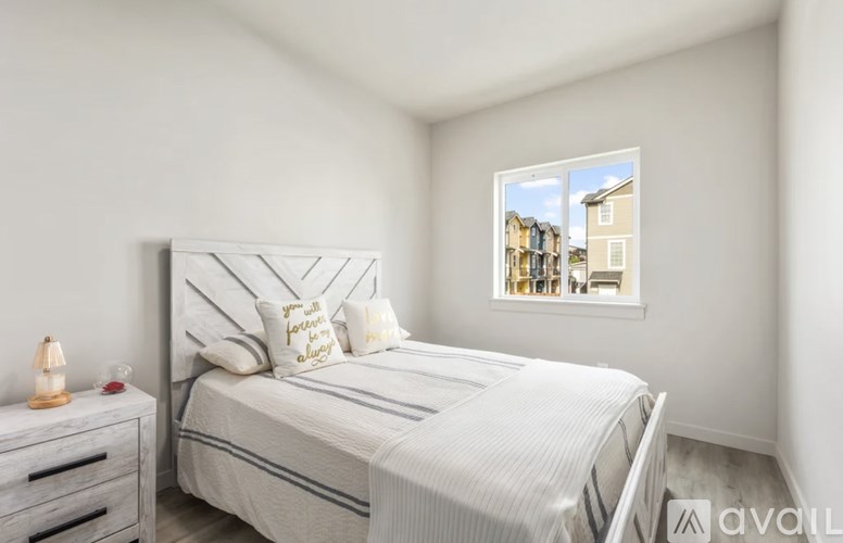 A bedroom with a bed, nightstand, and window showing a view of buildings outside.