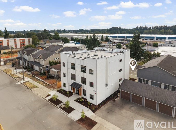 A large white building with a black roof is in the foreground of a sunny day.