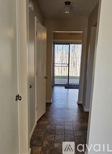 A hallway with a tiled floor and a door on the left.