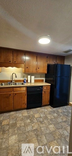 A kitchen with wooden cabinets and a black refrigerator.