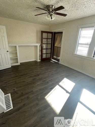 A room with a ceiling fan and wooden flooring.