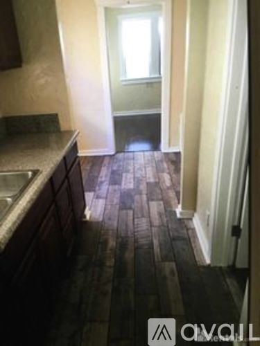 A hallway with a wooden floor and a doorway leading to another room.