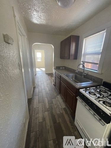 A kitchen with a white stove and wooden floors.