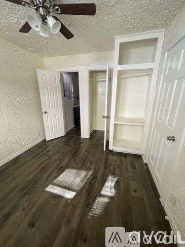 A room with a ceiling fan and wooden floors.