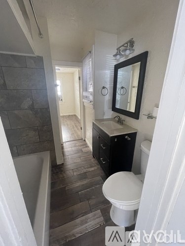 A bathroom with a toilet, sink, and a mirror.