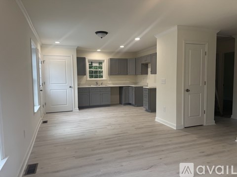 A spacious kitchen with grey cabinets and a white door.