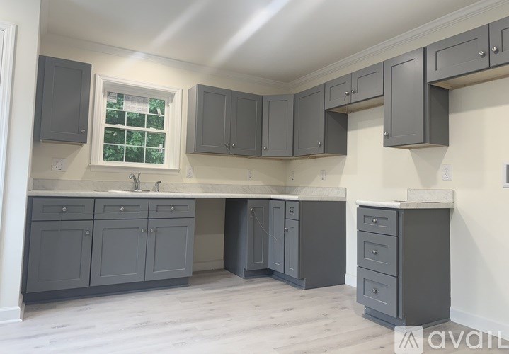 A kitchen with grey cabinets and a window.