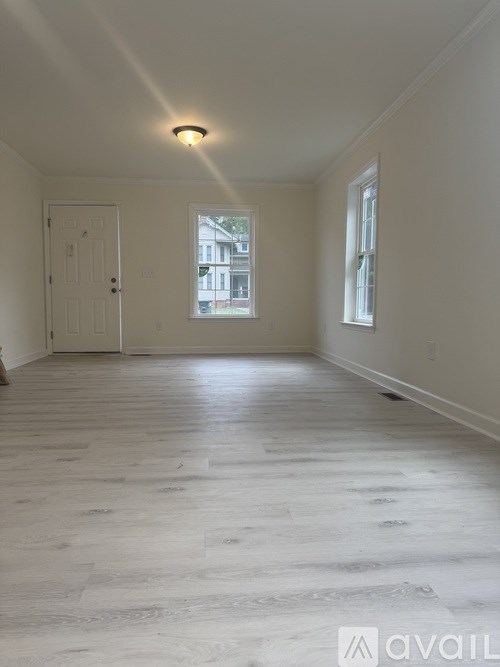 A room with a white door and a window with a view of a building outside.