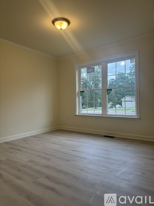 A room with a large window and wooden flooring.