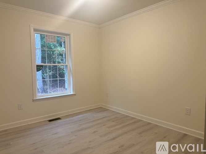 A room with a window and wooden flooring is available for rent.