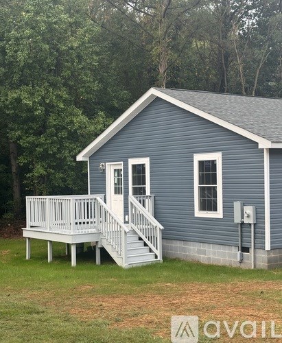 A small blue house with a white porch and stairs.