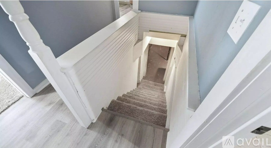 A staircase with a beige carpeted runner and white balusters.