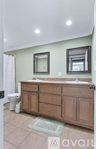 A bathroom with a toilet, sink, and mirror.