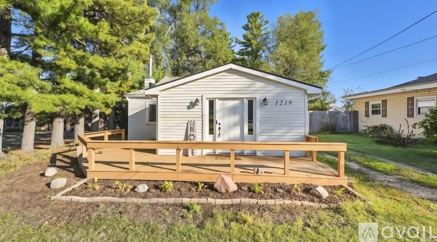 A small house with a wooden deck in the front yard.