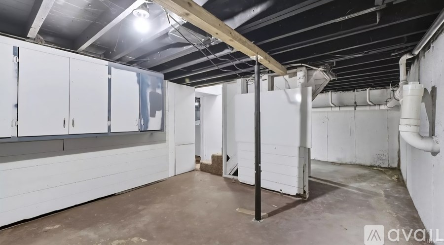A spacious, empty room with white cabinets and a concrete floor.