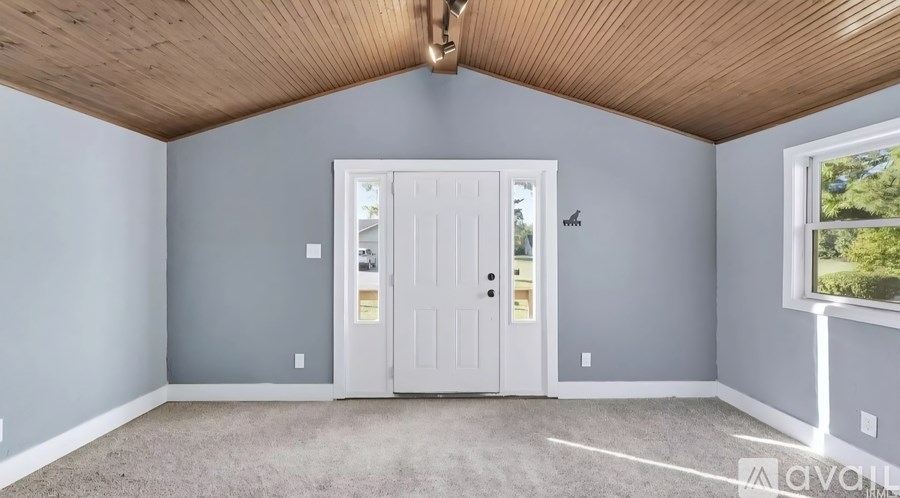 A room with a white door and a window showing trees outside.