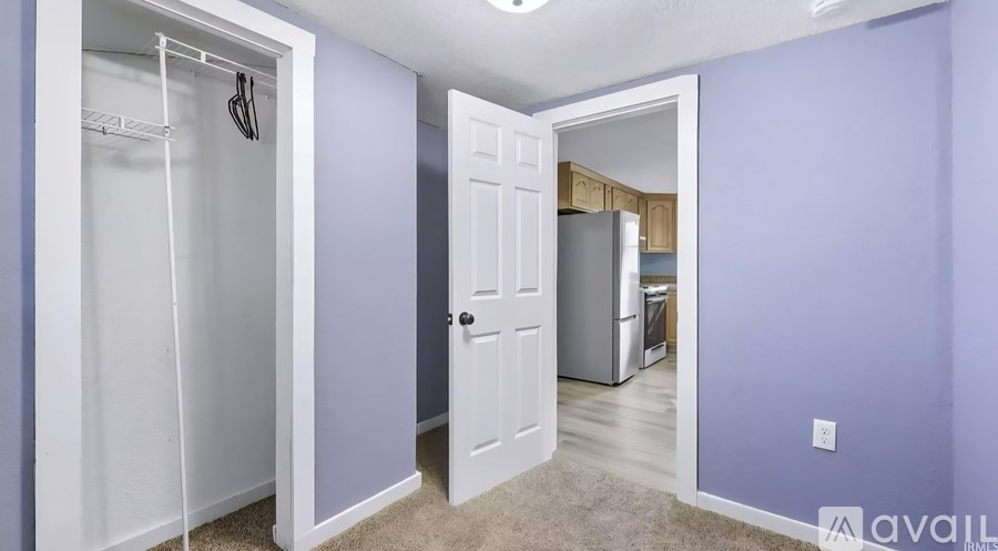 A white closet with a white door is open to a kitchen.