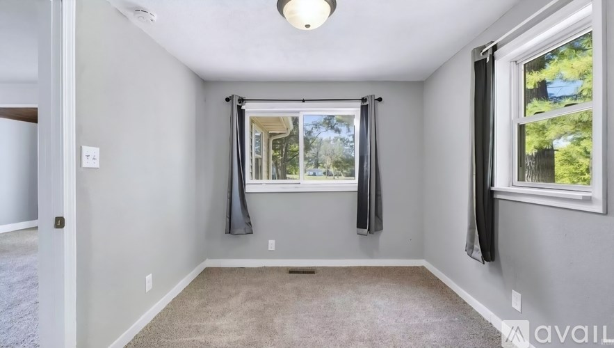 A room with a window and a carpeted floor.