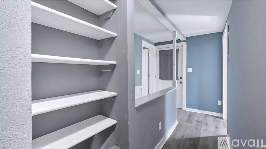 A hallway with white shelves and a door.
