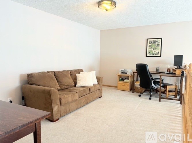 A living room with a brown couch and a desk with a computer.