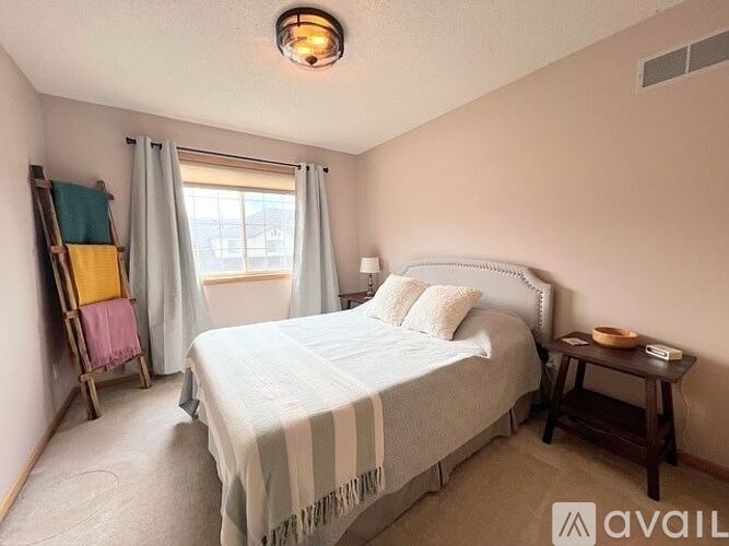A bedroom with a bed, nightstand, and window with curtains.