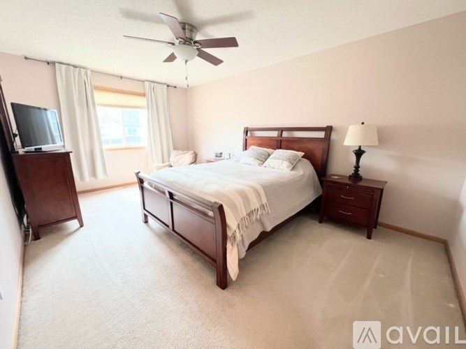 A bedroom with a large bed, a television, and a ceiling fan.