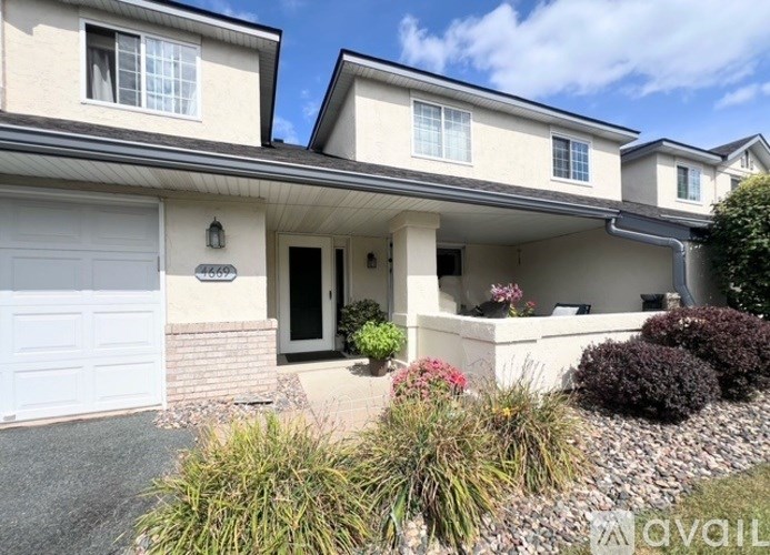 A two-story house with a garage and landscaping in front.