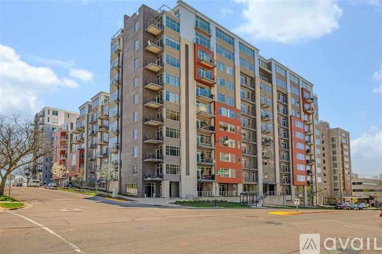 A large apartment building with multiple balconies and a parking lot in front.