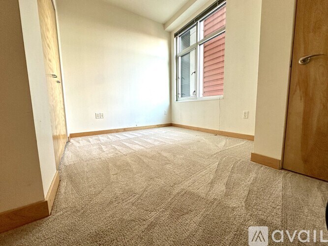 A room with a carpeted floor and a window with red blinds.