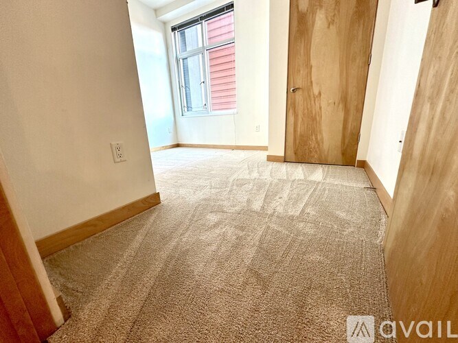 A room with a carpeted floor and a window with blinds.