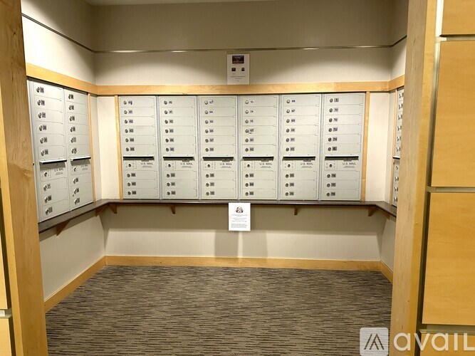A room with a carpeted floor and a wall of mailboxes.