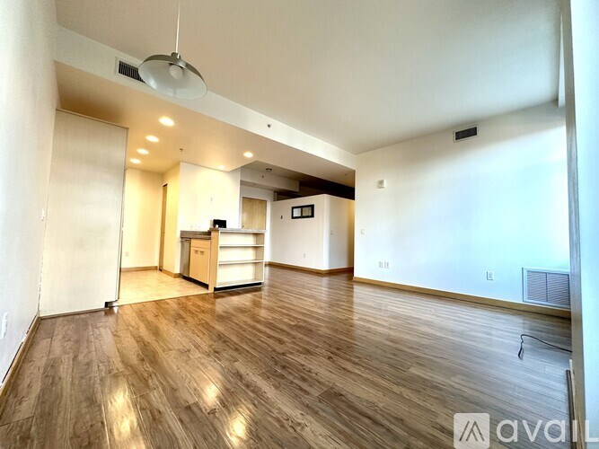 A spacious room with wooden flooring and a ceiling fan.