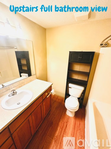 A bathroom with a toilet, sink, and mirror.