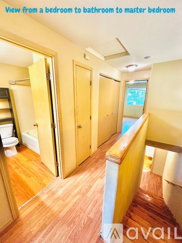A hallway with wooden floors and doors leading to a bathroom and a master bedroom.
