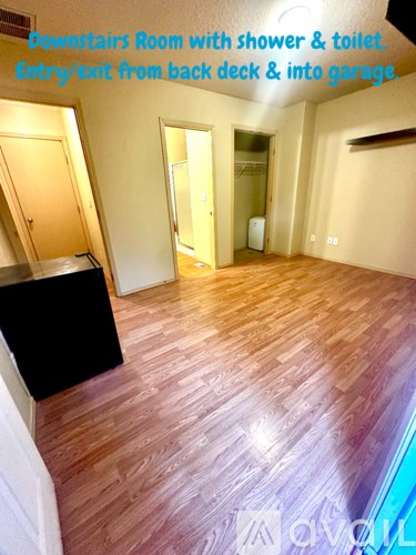 A room with a wooden floor and a shower and toilet in the corner.