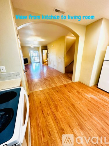 A kitchen with wooden floors and a view to the living room.