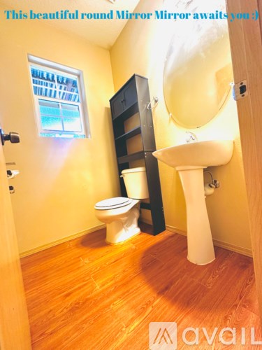 A bathroom with a round mirror and wooden floors.