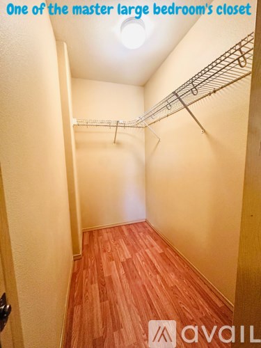 A large bedroom closet with a wooden floor and white walls.