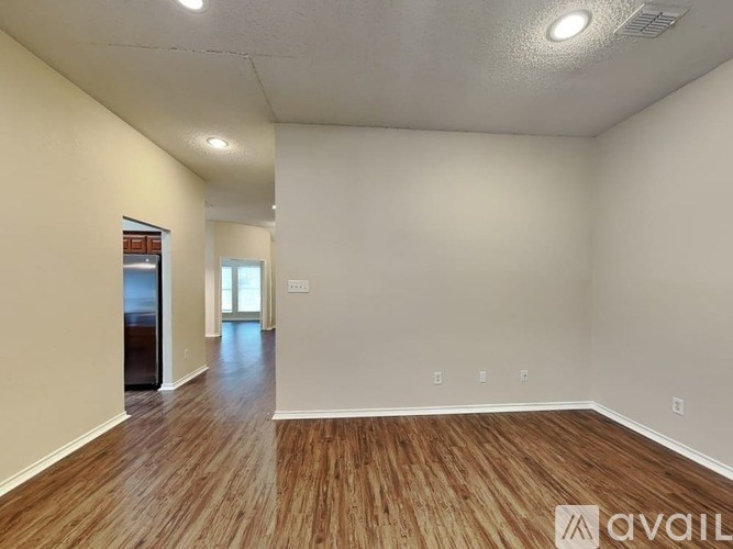 A spacious room with wooden flooring and white walls.