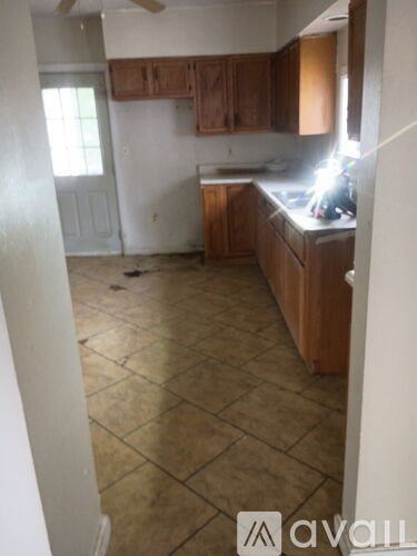 A kitchen with tile flooring and wooden cabinets.