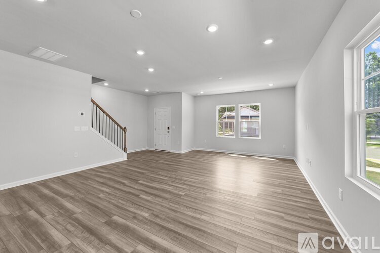 A spacious room with wooden flooring and white walls.