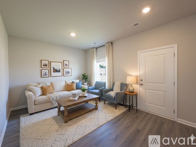 A living room with a white couch, a grey armchair, a wooden coffee table, and pictures on the wall.