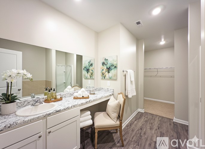 A bathroom with a vanity, a chair, and a towel rack.