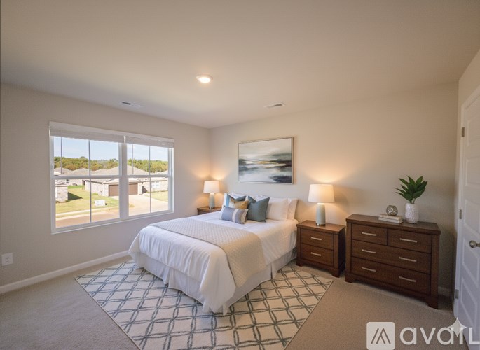 A bedroom with a large bed, two nightstands, and a window overlooking a street.