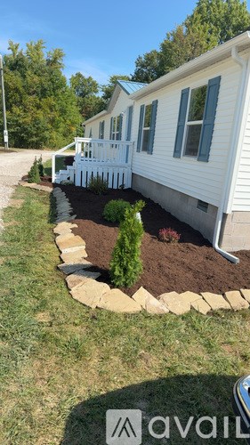 A white house with a blue awning and a small garden in front.